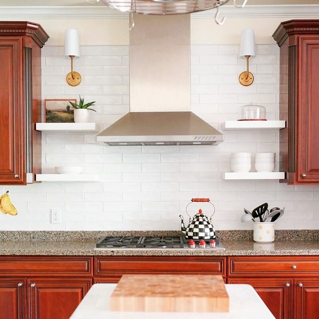 Tile backsplash: white ceramic subway tile behind a range with floating shelves